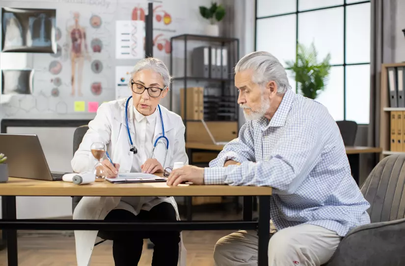 Paciente sentado juntamente com a médica, que está realizando a anamnese.