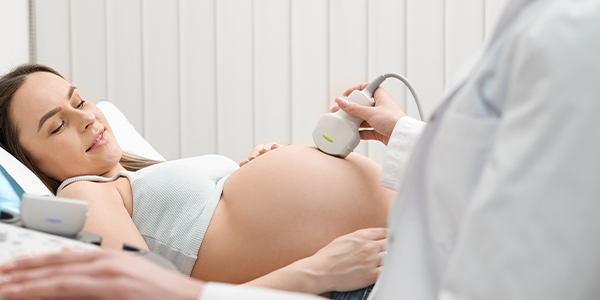 Obstetra examinando barriga de mulher grávida.