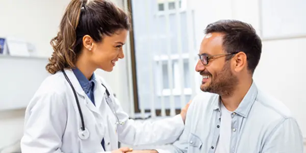 Profissional de saúde com um paciente em um ambiente clínico, documentando o histórico médico para diagnóstico preciso e planejamento de tratamento.